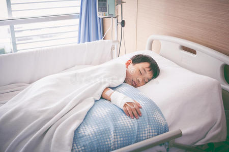 亚洲男孩躺在病床上，用生理盐水静脉注射。 健康
