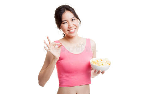 美丽的亚洲健康女孩吃薯片显示OK标志。