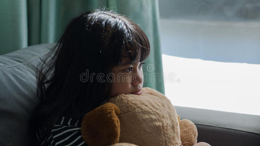 可爱的小女孩想着拿着一个洋娃娃,担心和悲伤照片