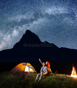 背包客女孩和男孩在晚上看着明亮的星空.