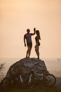 骑自行车的人站在靠近山地自行车的一块大石头上