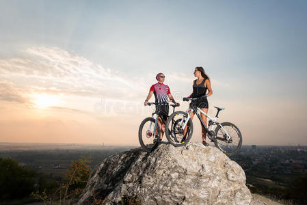 一对夫妇和自行车站在夜空下的岩石上