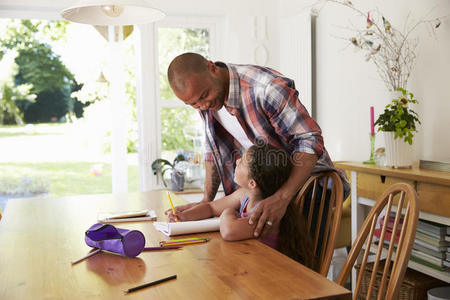 父亲在桌子上帮女儿做作业