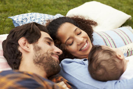 家庭和婴儿一起在花园的地毯上放松