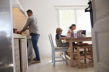 爸爸做饭，妈妈和孩子在厨房的桌子上，低角度
