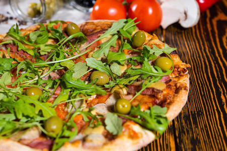 把比萨饼和阿鲁古拉和橄榄放在木桌上