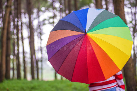 美丽的女人带着五颜六色的雨伞站在秋天的公园里