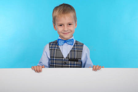一个微笑的小学生在白色广告牌后面摆姿势