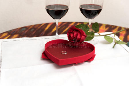 钻石戒指里面的红色玫瑰超过两个酒杯背景