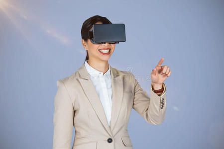 微笑的女商人在戴虚拟视频眼镜时指着的复合图像