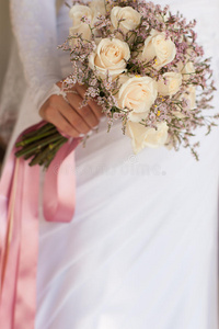 穿着白色连衣裙的新娘拿着结婚花束
