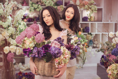美丽的亚洲女性花商很高兴在花店工作，有很多春天的花