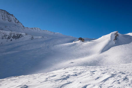 高山避难所在山岭以下的冬天,在风吹雪照片