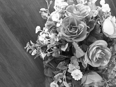 一束灰色的玫瑰假的放在木桌上沙漠玫瑰或黑斑羚百合或假杜鹃花玫瑰假