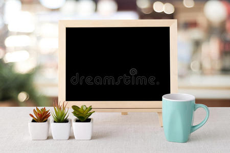 空白黑板和绿色咖啡杯站在模糊餐厅与Bokeh背景