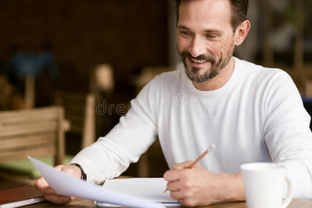 高兴的大胡子男人在咖啡馆里做笔记