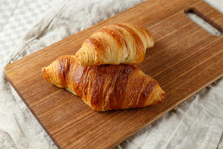 美味的法国新鲜烤牛角面包在一个木制的切割板上.照片