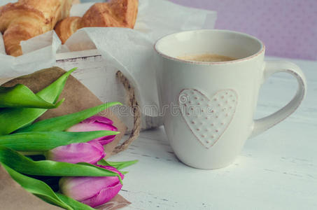 一杯咖啡和一束粉红色郁金香和羊角面包