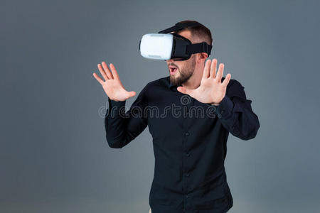 情绪化的年轻人使用VR耳机，在灰色背景下体验虚拟现实