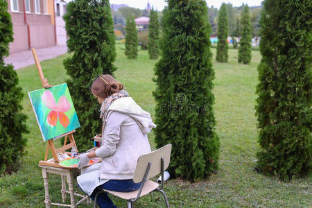 女孩艺术家画图片，坐在椅子上的画架两侧