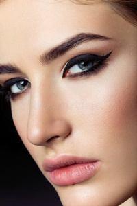 人穿着米色的风衣, 牛仔牛仔裤, 脚踝靴子, 猫眼太阳镜和一个金属手柄