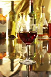 镜子桌子上的一杯红酒。 瓶子在背景上的酒吧里