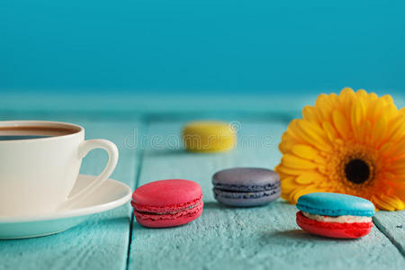 一杯咖啡或茶，蓝色背景上有黄花和马卡龙