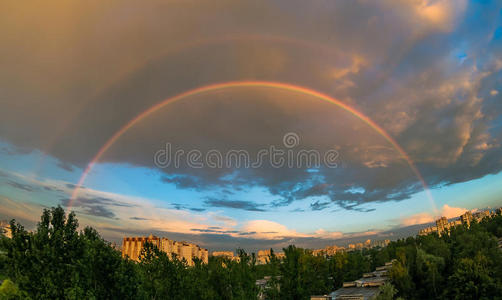 傍晚的彩虹在天空中，在城市的夕阳下，在夏天，在雨中