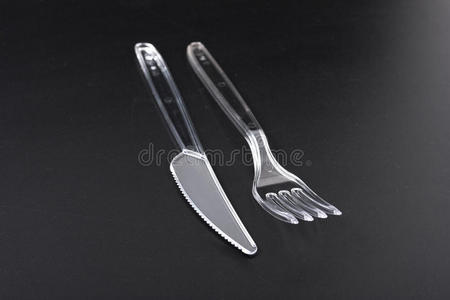 一次性塑料餐具。 黑色背景上的叉子和刀。