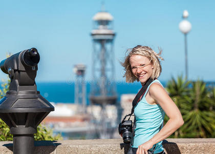 女旅行者站在巴塞罗那港的背景上，拿着相机