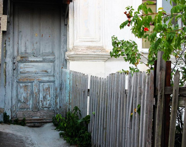 有灰蓝色门和栅栏的旧房子的正面。