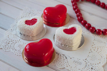 四个心形的红白蛋糕躺在白色的木桌上