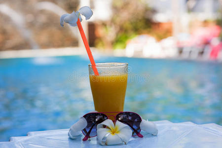 一杯芒果汁，在热带的一个豪华假期，在游泳池旁装饰着花梅菜太阳镜