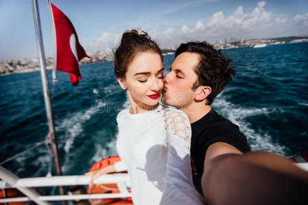 男孩和女孩，夫妇。 在船上做自拍游轮假期。 在土耳其国旗的背景下，大海和