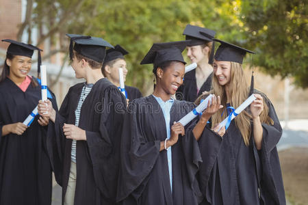 研究生学校的孩子们站在校园里拿着学位卷轴