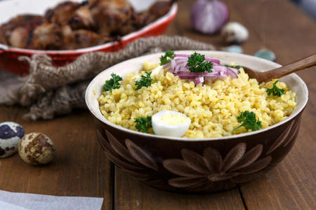 东方小麦东方传统小麦粥-bulgur,在一个粘土碗在黑暗的木制背景.照片