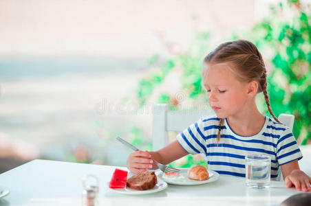 可爱的小女孩在咖啡厅吃早餐，海景