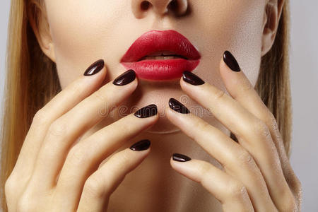 特写女性嘴唇与时尚红色化妆和指甲。 美丽的女性丰满的嘴唇与完美的化妆