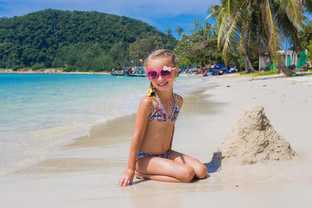 可爱的小女孩戴着太阳镜和泳衣在海边的天堂海滩上。 旅行和度假。 自由概念