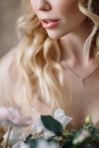 新娘早上。 很好的艺术婚礼。 一位年轻新娘的肖像，穿着白色新娘的肖像，波浪状的金发和一束花
