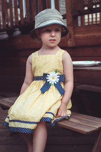 可爱的白种人女孩穿着黄色的衣服和帽子，在夏天的后院