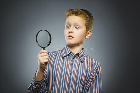 男孩透过放大镜看到，孩子的眼睛看着放大镜镜头超过灰色