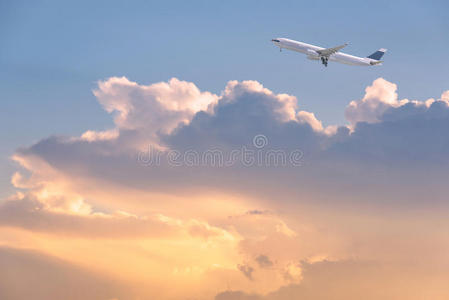 商业飞机飞越日出天空和云层。