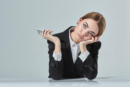 穿着黑色西装的有魅力的黑发女人坐在办公室的桌子上。