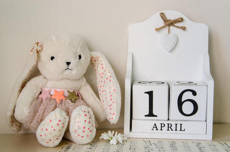 复活节兔子,鸡蛋和木制永久日历在白木背景16年4月16日神圣复活节2017
