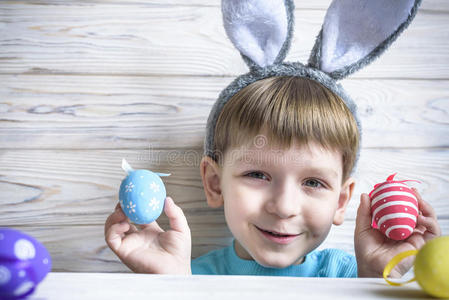 可爱的小男孩在复活节那天在家里抱着一个带着彩色复活节彩蛋的巢.