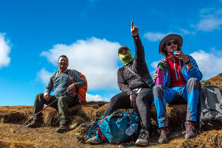 一群旅行者躺在山上的小径上,手朝前照片