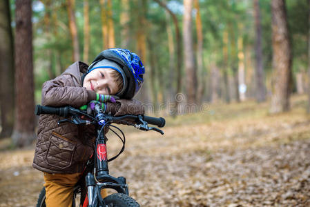 清晨，孩子骑自行车在森林里。 男孩骑自行车