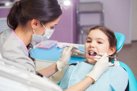 在牙医治疗她的牙齿时，一个漂亮的小女孩张开了嘴