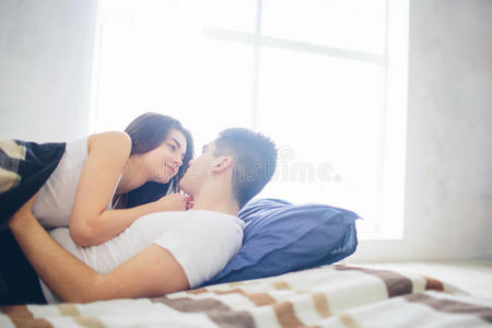 一对恩爱的夫妇躺在床上。 明亮舒适的卧室。 家庭的安慰和爱